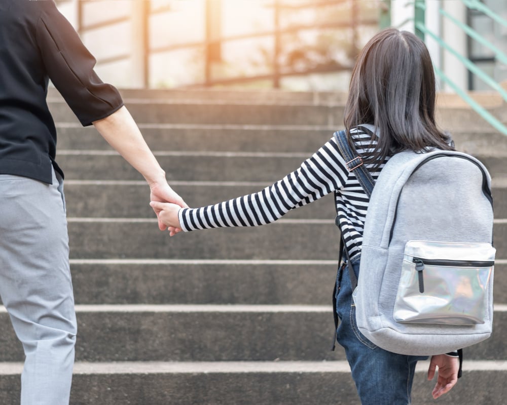 Child holding parent's hand on first day at new school