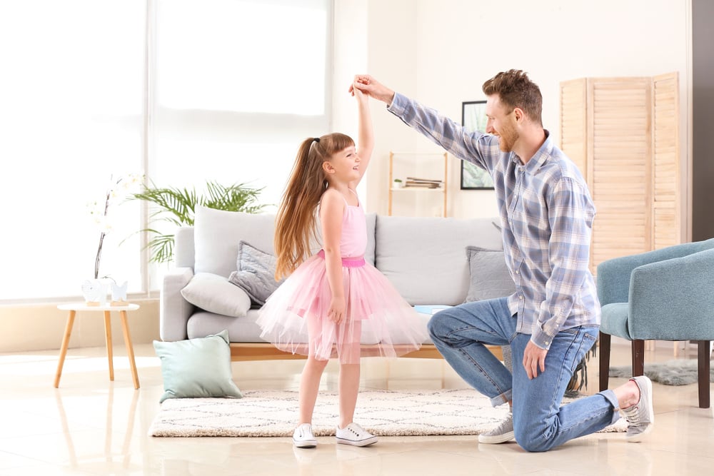 Happy father and his little daughter dancing at home