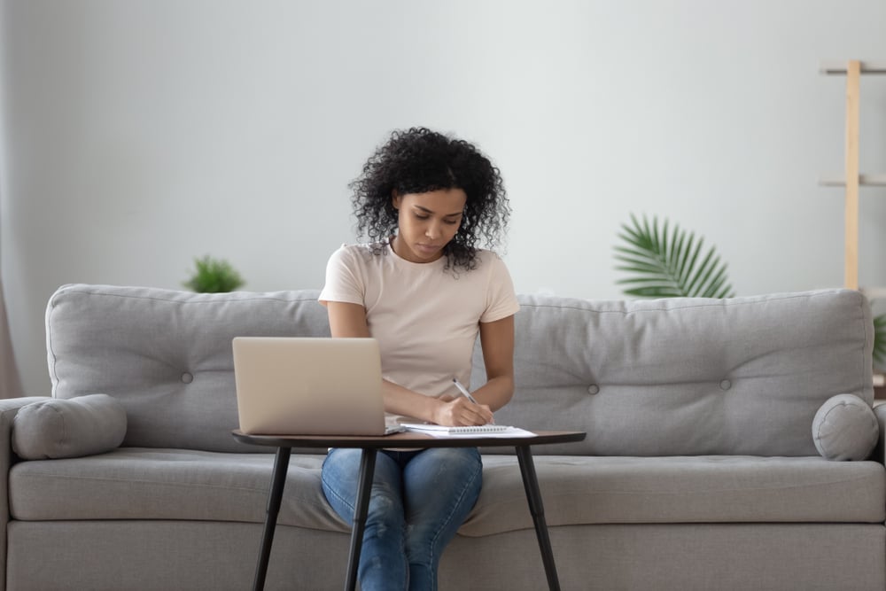 Woman sitting on couch writing list