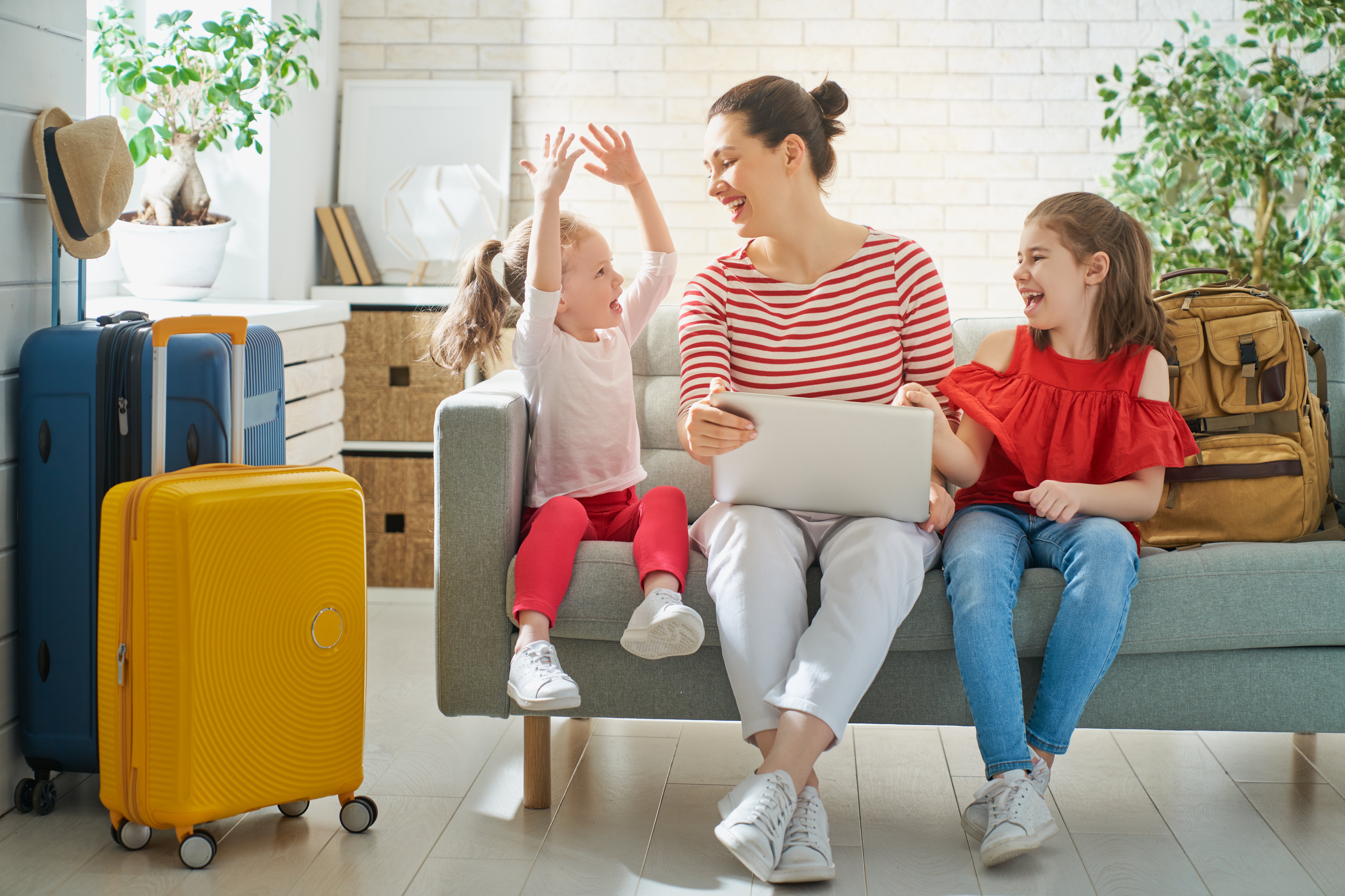 Go on an adventure! Happy family preparing for the journey. Mom and daughters are packing suitcases for the trip.