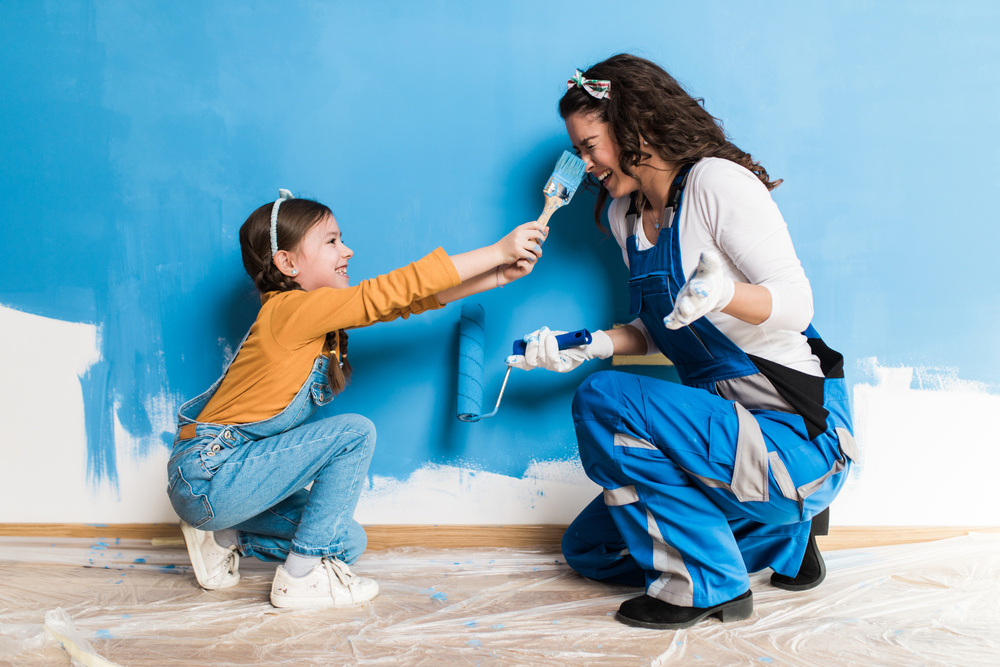 Mother and daughter laughing while painting wall