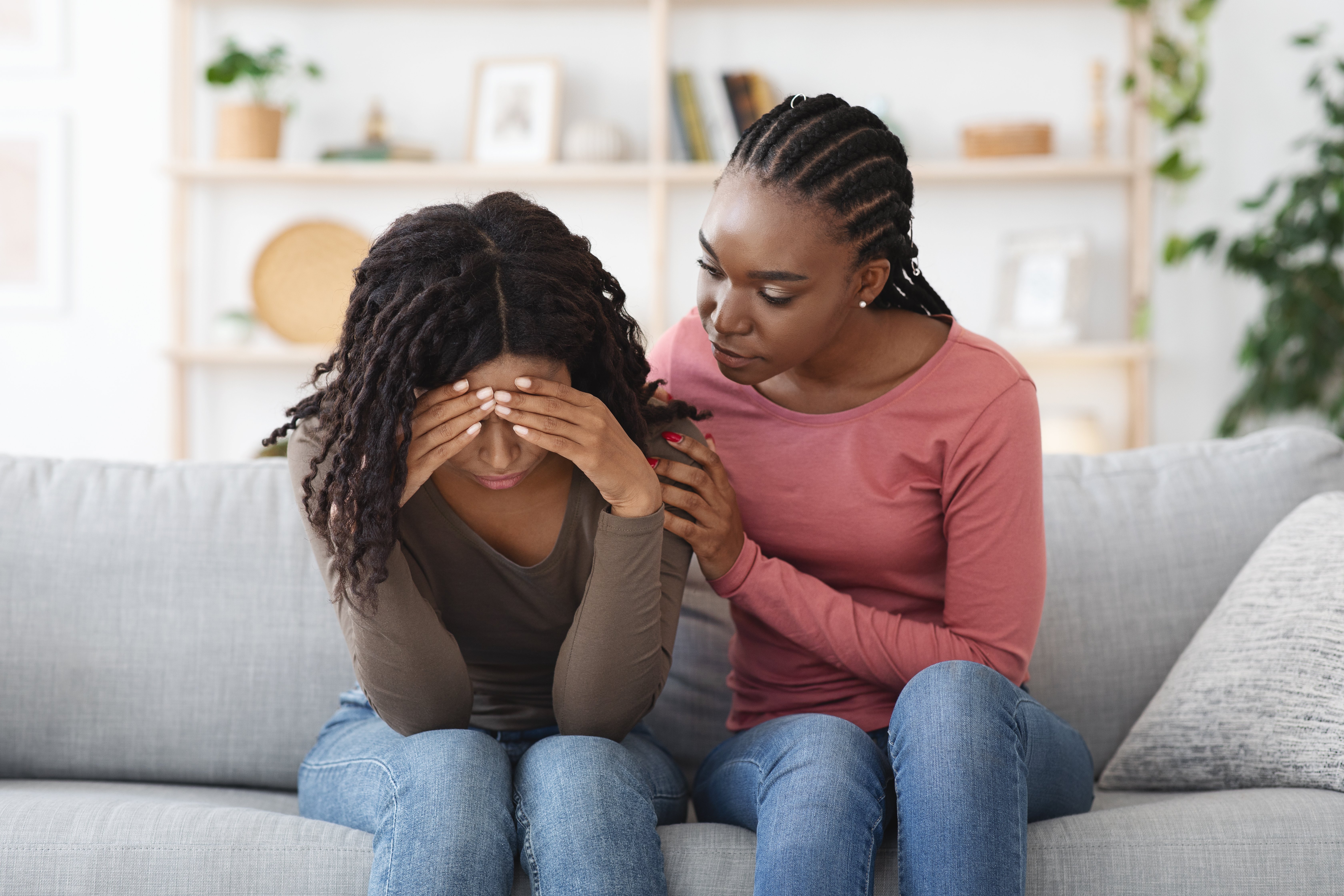 Attentive african american lady comforting her upset crying girlfriend or sister, giving her hug, saying supportive words.
