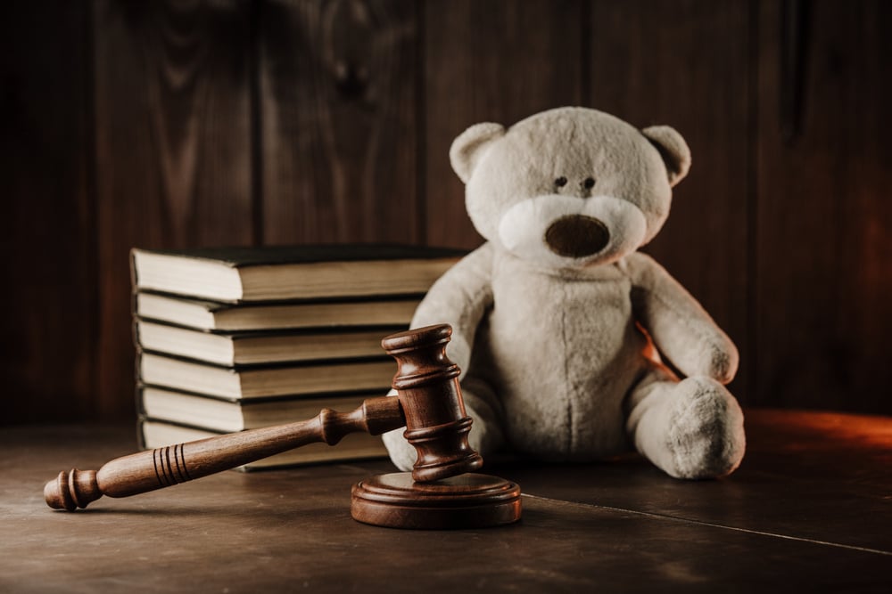 Divorce and alimony concept. Wooden gavel and teddy bear as symbol of child