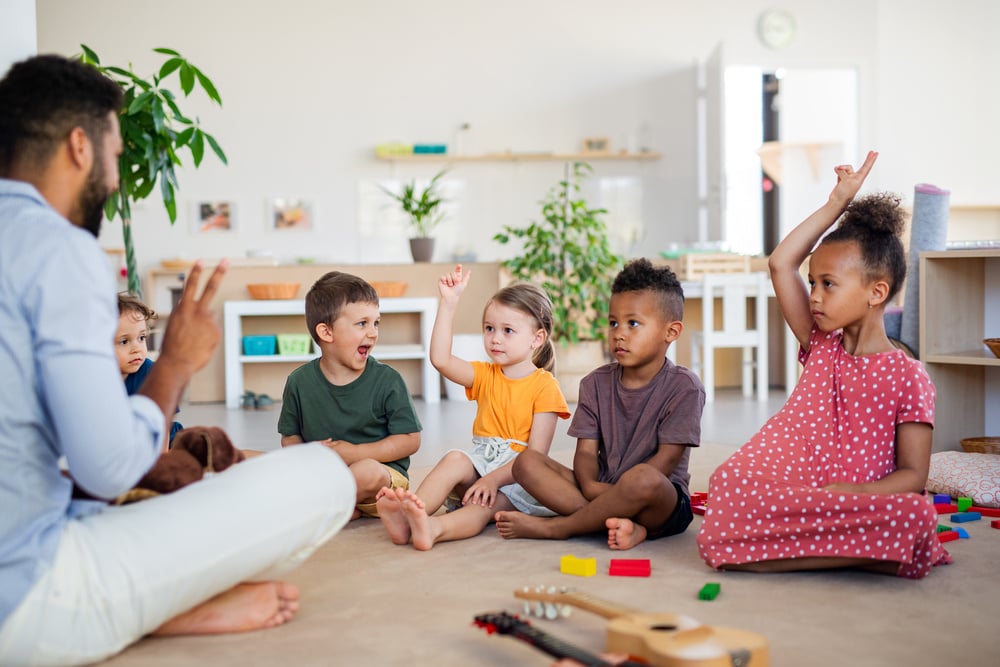 Group of small nursery school children sitting on floor indoors in classroom.