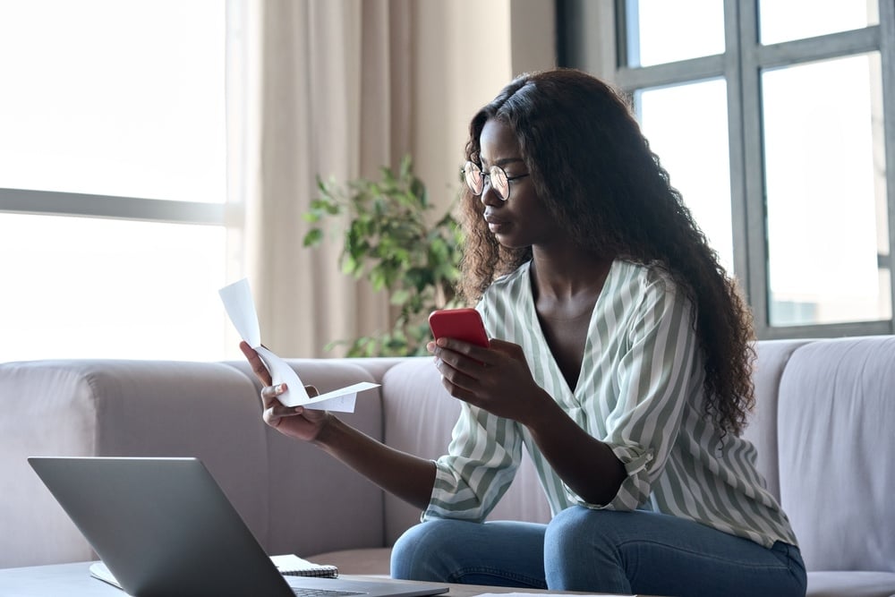 Serious young black African woman holding paper filing taxes