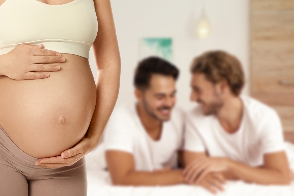 Surrogacy concept. Young pregnant woman and blurred view of happy LGBTQ+ couple