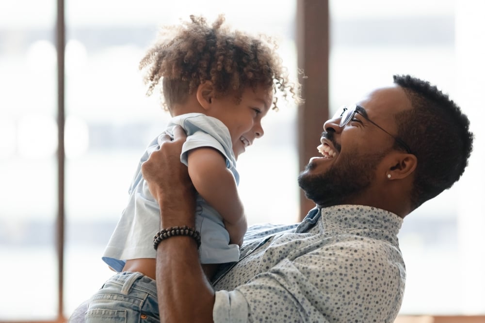 Happy African-American dad holding toddler in his arms