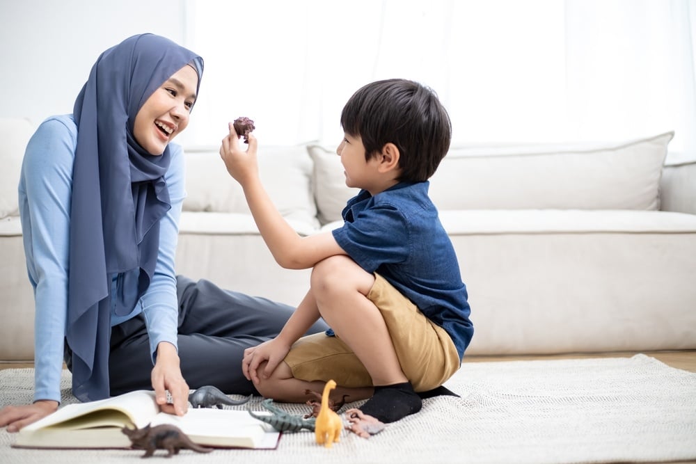 Muslim babysitter Group of small nursery school children sitting on floor indoors in classroom.