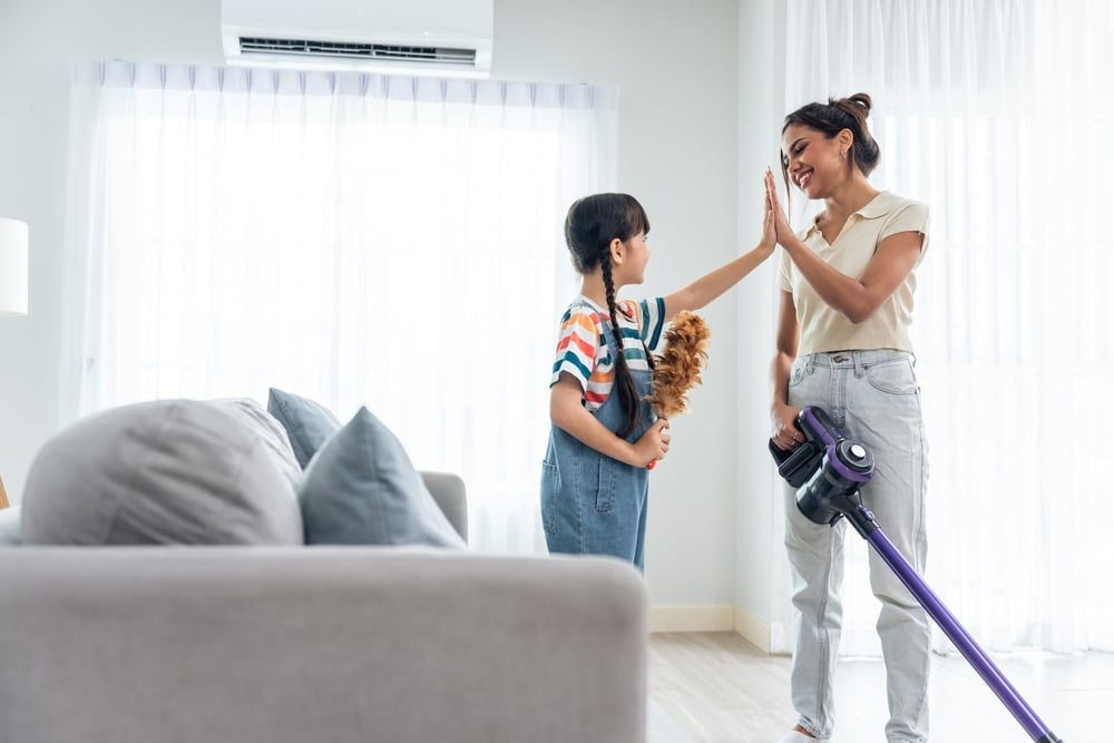 Mother and daughter high fiving while cleaning house