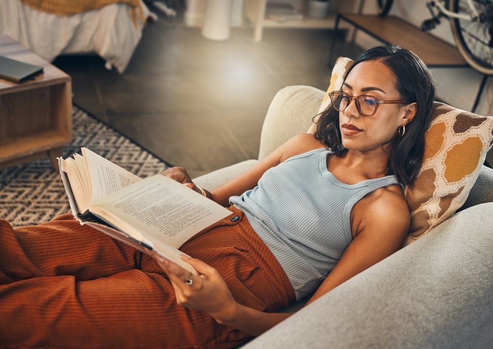 Woman relax on sofa, reading book at house