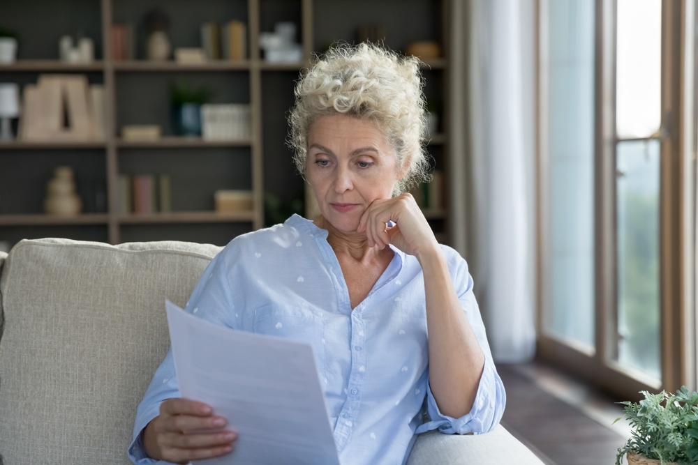 Serious blonde senior woman reviewing paperwork