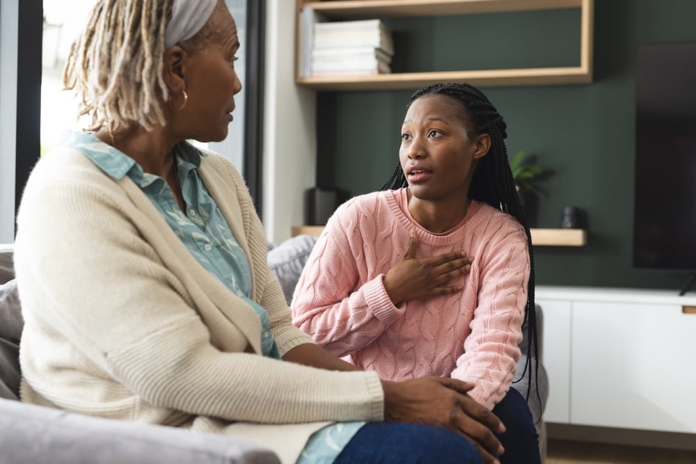 African American senior mother sitting and talking with adult daughter