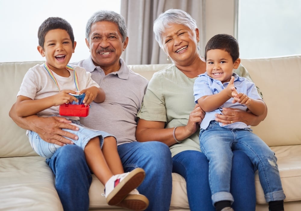 Grandparents, portrait and children with family, fun and bonding together in home with smile. Care, love and support with generations, senior people and young boys on living room sofa with laugh