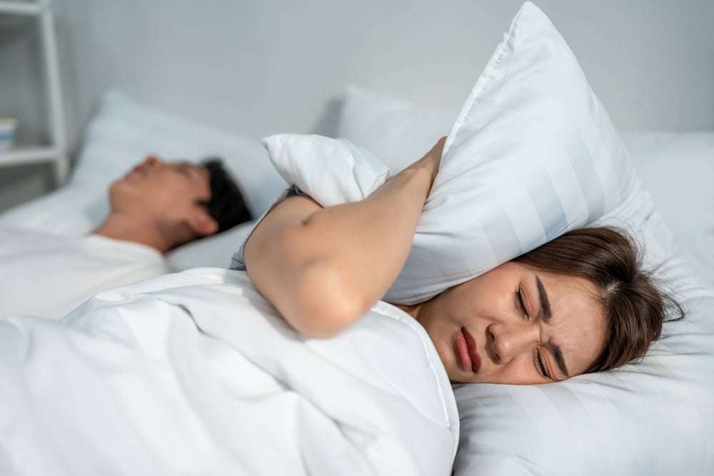 Asian beautiful woman feel frustrated from husband snoring while sleep.