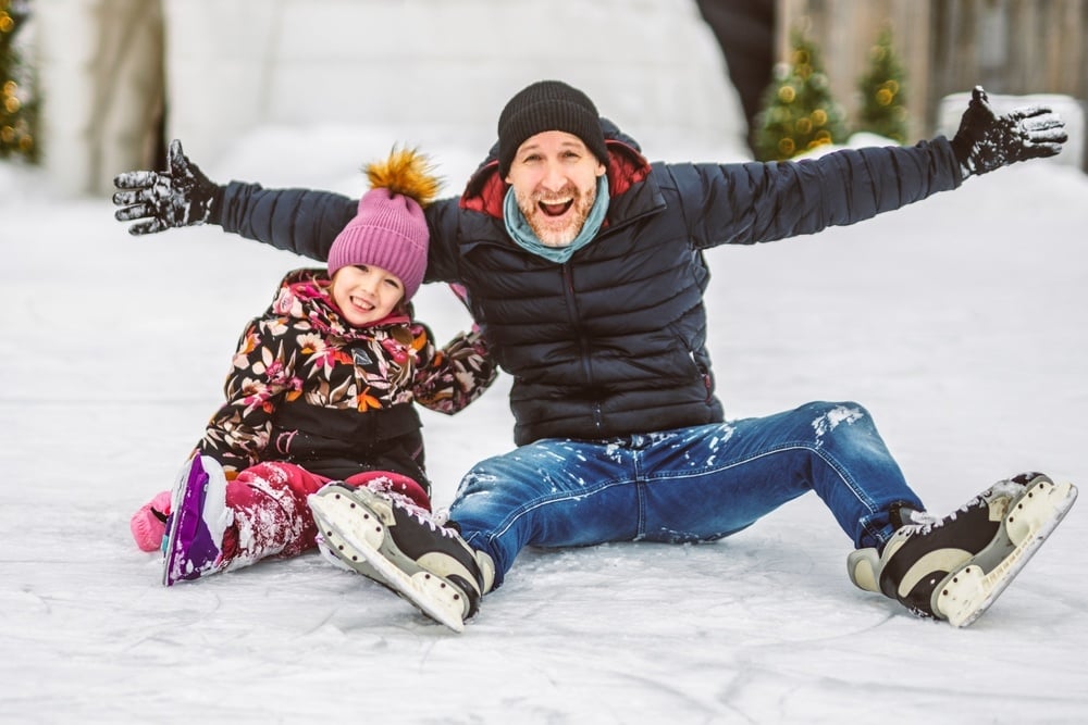 A Happy father and daughter on winter day learning skating