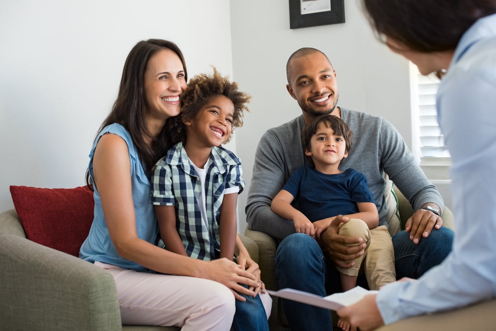 Multi-ethnic family sitting on couch smiling
